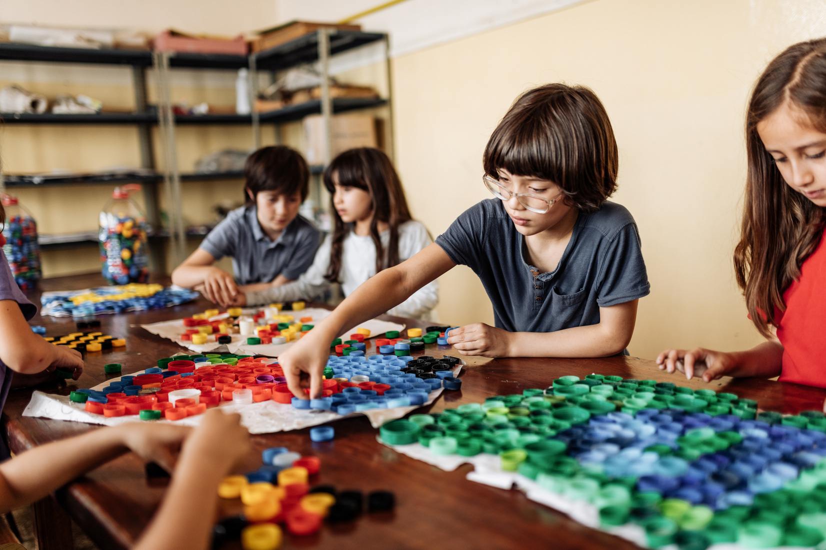 Elementary school pupils creating art product from recycled plastic